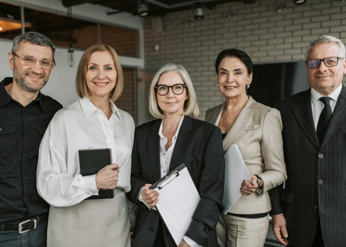 A diverse team of senior business professionals posing confidently indoors.