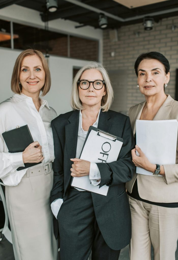Group of senior female professionals confidently posing in office setting.